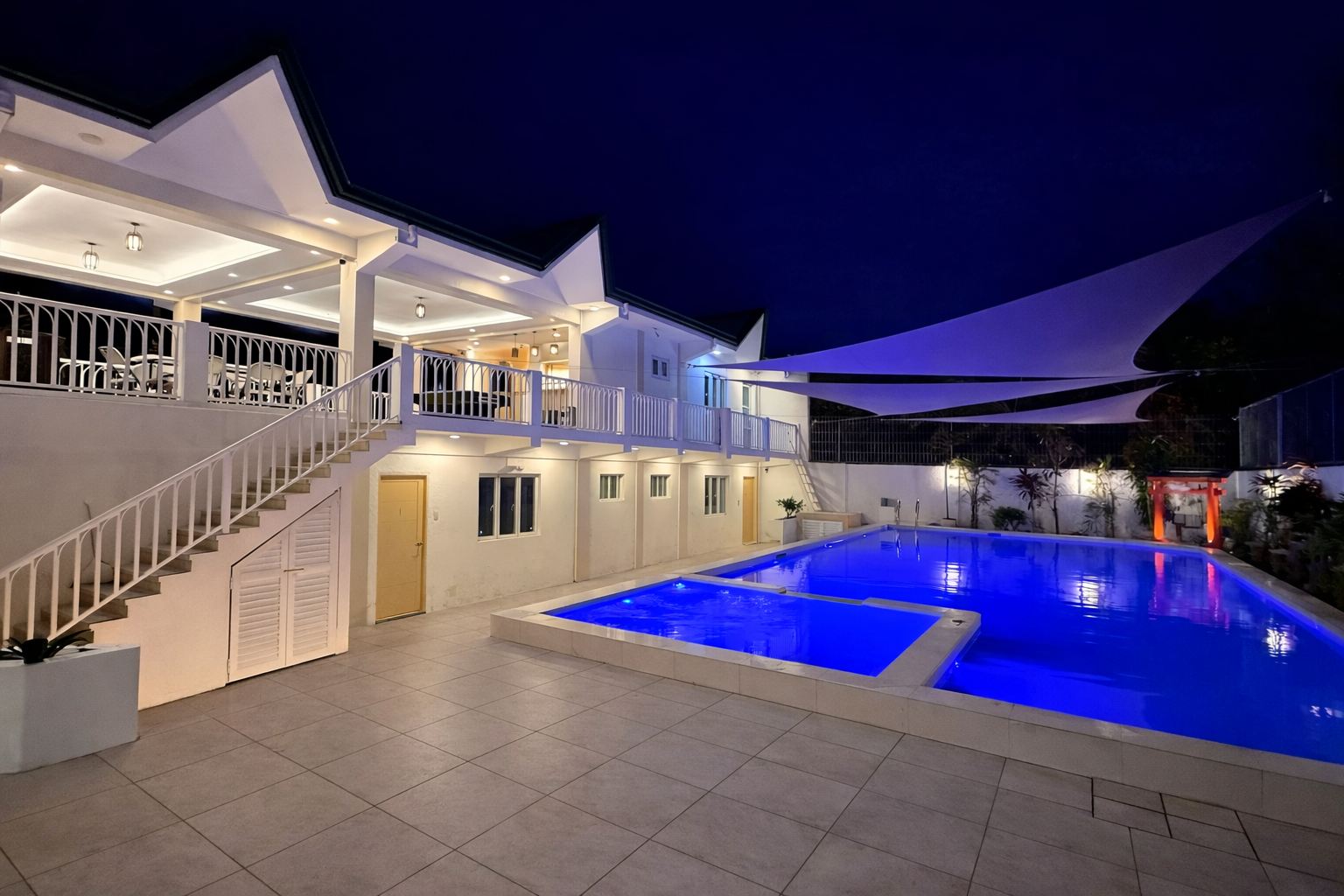 Casa Sakura's hot spring pool lit up at night under white sail shades